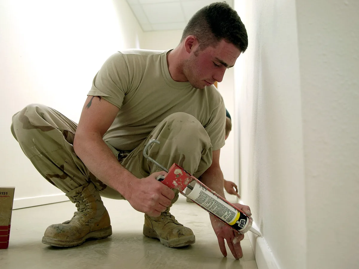 A caulk gun and a roll of V-strip weatherstripping